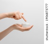 Small photo of Thick hand cream on a woman's palm, 2nd hand finger takes a drop of cream. Groomed hands, natural short nails, on a light background.