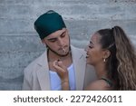 Small photo of Latino and Hispanic boy and girl couple, young and nonconformist, rebellious, hugging while she lights a cigarette for him. Concept tobacco, smoke, fire, addiction, gangs, couples.
