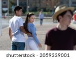 Small photo of Unfaithful teenager girl walking with boyfriend and looking to another boy. Disloyalty concept.