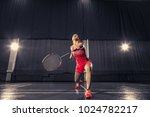 Young woman playing badminton over gym background