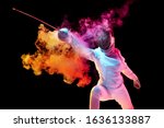 Small photo of Contrasts. Teen girl in fencing costume with sword in hand isolated on black background, neon lighted smoke. Practicing and training in motion, action. Copyspace. Sport, youth, healthy lifestyle.