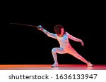 Small photo of Forward. Teen girl in fencing costume with sword in hand isolated on black background, neon light. Young model practicing and training in motion, action. Copyspace. Sport, youth, healthy lifestyle.