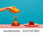 Small photo of French breakfast. Female hand tasting crispy croissant on plaid tablecloth isolated on bright blue background. Vintage, retro style interior. Complementary colors, Copy space for ad, text