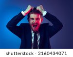 Pull hair on head. Excited young stylish man in business suit shouting isolated on dark blue studio background. Concept of human emotions, facial expression, sales, ad, fashion and beauty