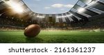 Small photo of Opening season of games. Leather american football ball on grass of football field at stadium with spotlight. Concept of sport, art, energy, power. Poster for ad, design