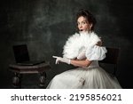 Small photo of Wow, shock. Creative portrait of young beautiful girl elegant dress of medieval fashion style with veer isolated on dark background. Comparison of eras concept, flemish style. Classic art character
