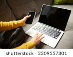 Woman's hands using phone and laptop making online order, checking purchase, shopping at home, indoors. Concept of startup, small business. Entrepreneur owner. Black Friday or cyber Monday