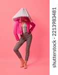 Small photo of Weird people concept. Creative portrait of young girl in avant-garde style image isolated over pink background. Vivid style, queer, art, fashion Stylish model in white lampshade.