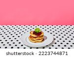 Plate of delicious sweet pancakes with jam on dotted white tablecloth over pink background. Vintage, retro style interior. Food pop art photography. Complementary colors. Copy space for ad, text