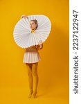 Small photo of Sunny. Young indifferent girl in giant jabot collar or neckwear and yellow tights isolated over yellow background. Contemporary art, weird beauty, avant-garde fashion.