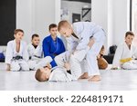 Small photo of Little boys, children in white kimono training judo, jiu-jitsu indoors. Professional sports club for kids. Concept of martial arts, combat sport, sport education, childhood, hobby
