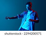 Small photo of Inner sense, intuition. Young man in casual clothes with closed eyes standing with digital neon filter light reflection over blue background. Concept of modern photography, art, cyberpunk, creativity