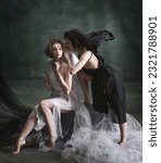 Small photo of Devilish woman whispering to naive angel. Portrait of two women, angel and demon against dark, green, vintage background. Concept of history, remake, good and bad, creative photography