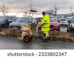 Small photo of Sweden, Knislinge – January 3, 2023: A man in uniform picking up rubbish, cleaning up streets. Scavenger, dustman, garbage collector, ashman.