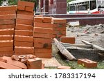 Small photo of A pile of red bricks at a construction site in the city. Reupload the wall of bricks with cement in construction. Repair, industrial brickwork parts, construction equipment.