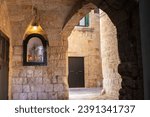 Small photo of Catholic chapel with Saint. Antonym holding baby Jesus and bible, alley with stone arch and stone houses