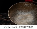 Small photo of Drops of water fly into the air from hitting a Tibetan (singing) bowl. Cold boil. Tibetan bowl on a black background. High quality photo