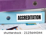 Small photo of A lignt blue folder with the label ACCREDITATION.