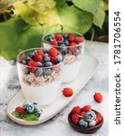 Small photo of Healthy breakfast. Two glass glasses with yogurt, muesli and fresh berries are on an elongated plate. Nearby are fresh blueberries and raspberries. Summer light breakfast in nature. Healthy diet.