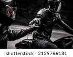 fist bump greeting of two motorbike riders in leather clothes and helmets 