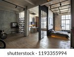 luxury studio apartment with a free layout in a loft style in dark colors. Stylish modern kitchen area with an island, cozy bedroom area with fireplace and personal gym