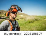 Small photo of Portrait of a workerman wearing hardhat, ear muffs, harness and sunglasses, during a sunny spring afternoon outdoors.