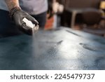 Small photo of A tattoo artist is cleaning the studio stretcher with a spray