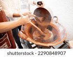 Small photo of Two Hispanic woman are preparing mole sauce in a big traditional clay casserole