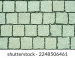 Granite cobblestone pavement background. Stone pavement texture. Abstract background of cobblestone pavement close-up. Seamless texture. View from above onto stone pavement of urban street. 