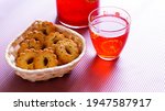 Small photo of jug and a glass with cranberry juice next to a plate with shortbread cookies on a pink phoneme and light from the window