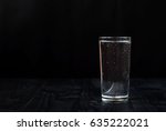 Just a glass of water on a dark wooden table. Mineral water in a glass on a black background. A glass with water.