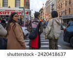 Small photo of New York, NY, USA 11-09-2023 Woman in a stylish artsy jacket decorated with a large trippy eye waits to cross a busy intersection on a Chinatown street. Editorial use only.