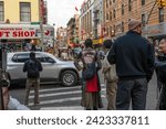 Small photo of New York, NY, USA 11-09-2023 Woman in a stylish artsy jacket decorated with a large trippy eye waits to cross a busy intersection on a Chinatown street. Editorial use only.