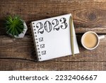 New year goals 2023 on desk. 2023 goals list with notebook, coffee cup, plant on wooden table. Resolutions, plan, goals, action, checklist, idea concept. New Year 2023 template, copy space