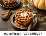 Small photo of waffles made from pumpkin puree, eggs and flour, with the addition of cinnamon, cloves. A cinnamon stick and a clove are lying next to each other