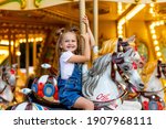 happy girl in an amusement park rides a horse on a carousel in the summer