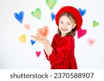 Small photo of valentine's day, a small smiling child girl in a red beret holds her hand for a place for a text or object and rejoices against the background of colorful hearts.