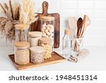 Assortment of grains, cereals and pasta in glass jars and kitchen utensils on wooden table. Healthy balanced food, sustainable lifestyle, zero waste storage, eco friendly idea