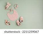 Small photo of Baby shoes, bib and teethers on pastel background. Organic newborn gifts, accessories, branding, small business idea. Baby shower invitation, greeting card. Flat lay, top view