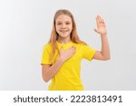 Small photo of Smiling teen girl wearing casual yellow t shirt, swearing with hand on chest and open palm, making a loyalty promise oath, promising to be honest, telling truth. White background