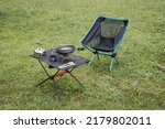 Small photo of Camping furniture, compact equipment, camping equipment, camping utensils are on the table, a folding chair, a gas burner, a kettle. High quality photo