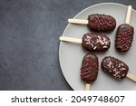 Chocolate cake pops in the form of ice cream on a stick. On a plate on a grey background. Concept food, sweets. Top view.