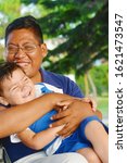 Small photo of Tender portrait od native american man with his little son in the park.