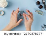 Small photo of Attaching candle wick into a jar, candles making. Woman hand making candle. Flatlay, top view. Blue background