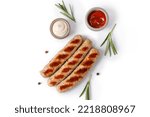 Grilled sausages isolated on white background with rosemary and sauces, top view, copy space. BBQ