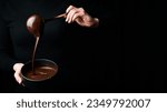 Small photo of The chef scoops hot chocolate into a bowl. On a black background. Preparation of chocolate.