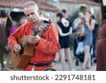 Small photo of Bazoges-en-Pareds, France - July 29 2017: A medieval minstrel playing guitar during the annual 'Nocturnes Medievales' festival.