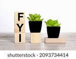 Small photo of FYI. text on wooden boards on a white background on a wooden table