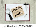 Small photo of Promissory note. wooden blocks with text. on a red notebook