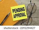 Small photo of pending approval words on a small sheet of paper placed on a yellow notepad